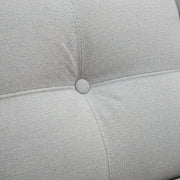 Close-up of a light gray cushion with a button on a textured fabric background