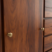 Close-up of a wooden cabinet with brass knobs