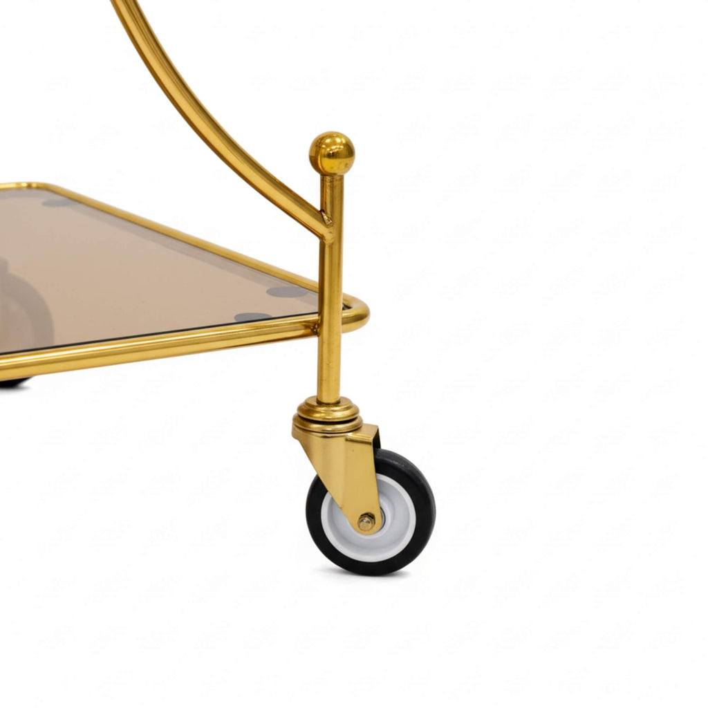 Gold bar cart with a clear glass shelf on a white background