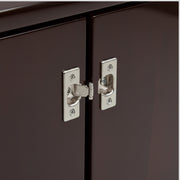 Close-up of metallic cabinet hinges on a dark brown cabinet door.