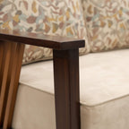 Wooden table leg with a beige sofa and patterned cushion in the background