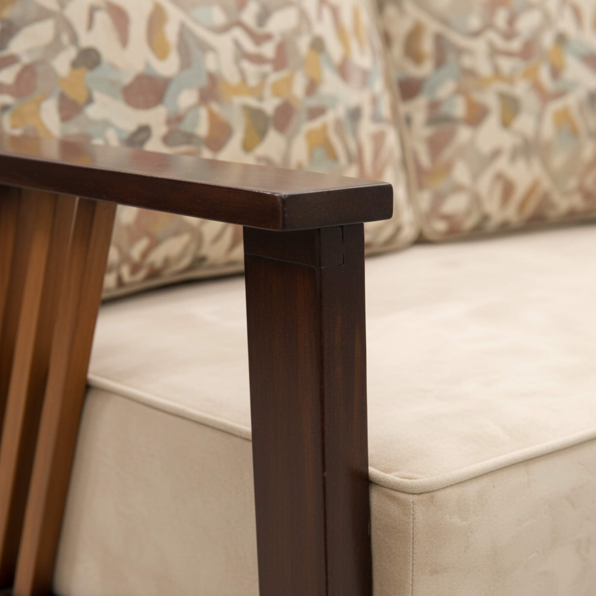 Wooden table leg with a beige sofa and patterned cushion in the background