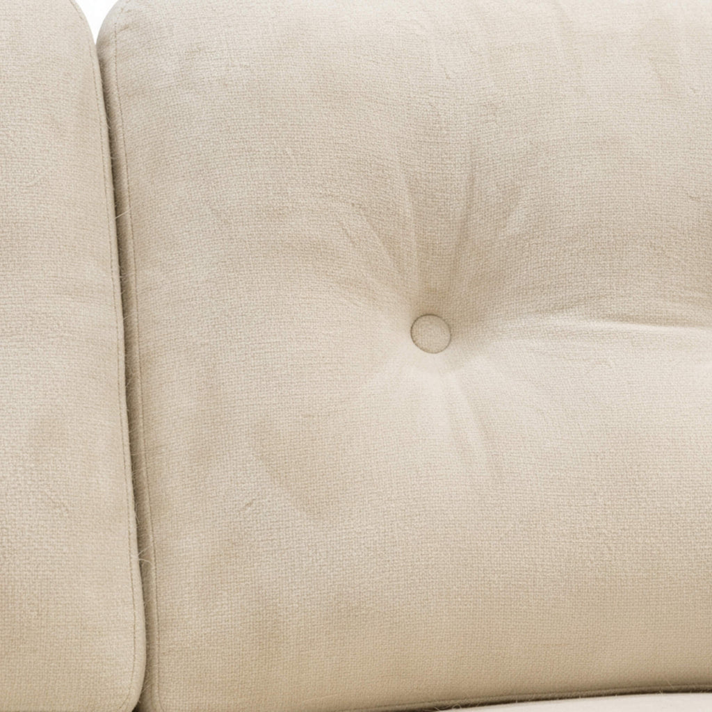 Close-up of a beige upholstered chair with tufted backrest
