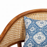 Blue patterned pillow on a wicker chair with a white background