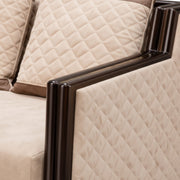 Close-up of a beige quilted sofa with dark wooden armrests
