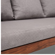 Gray cushioned outdoor sofa with wooden legs on a neutral background