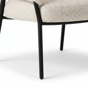 Chair with black metal legs and beige cushioned seat on a white background