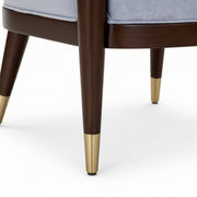 Close-up of a chair with wooden legs and gold accents on a white background