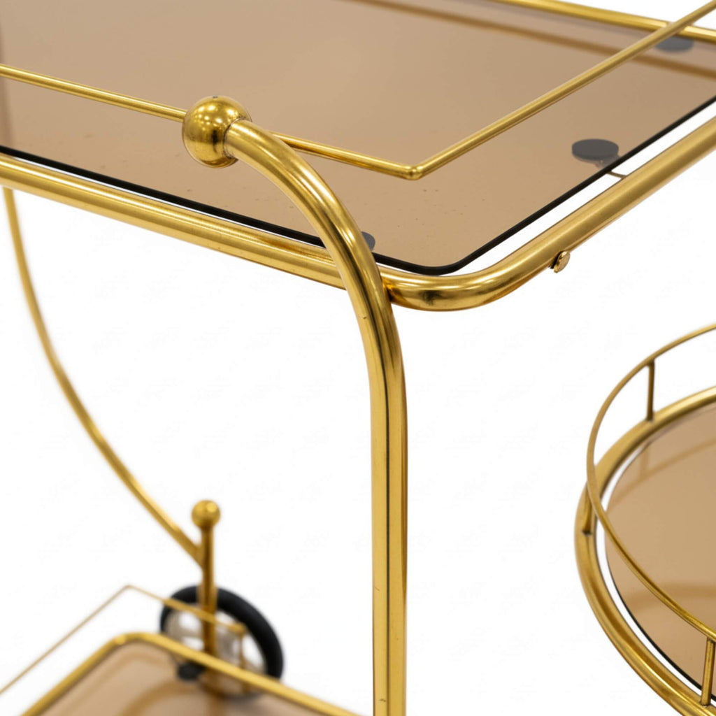 Gold bar cart with glass top and round tray on a white background