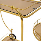 Gold bar cart with glass top and round tray on a white background