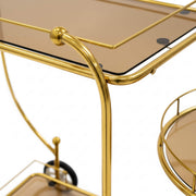 Gold bar cart with glass top and round tray on a white background