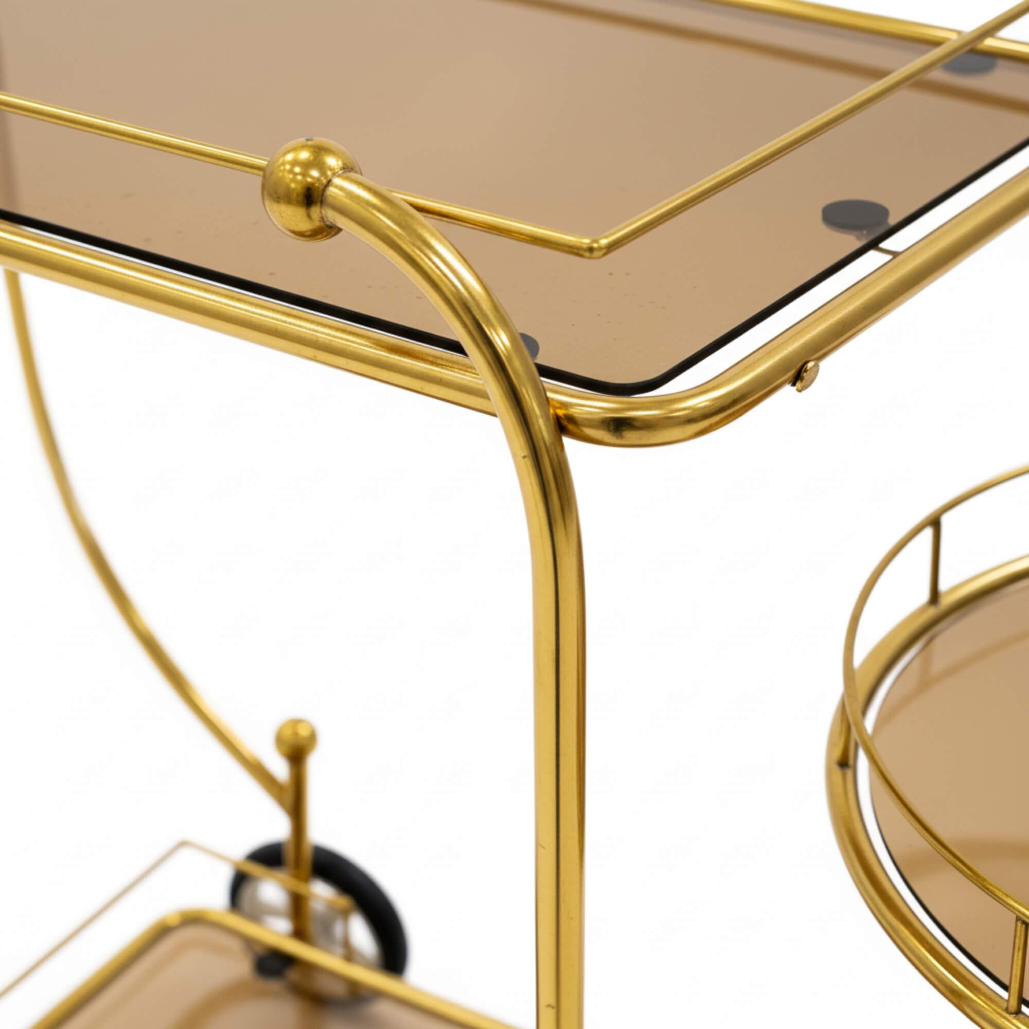 Gold bar cart with glass top and round tray on a white background