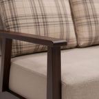 Close-up of a sofa with plaid patterned cushions and wooden armrest.