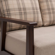 Close-up of a sofa with plaid patterned cushions and wooden armrest.