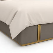 Bed with beige bedding and a gold accent on a white background