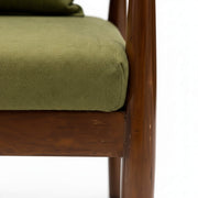 Close-up of a wooden chair with a green cushion on a white background