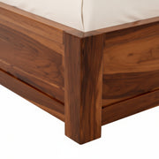 Close-up of a wooden bed frame with a white mattress.