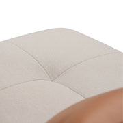Close-up of a beige fabric ottoman with tufted design on a white background