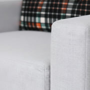 Gray sofa with a plaid pillow in the background