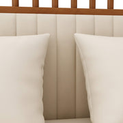 Two pillows on a bed with a wooden headboard and beige upholstered headboard.