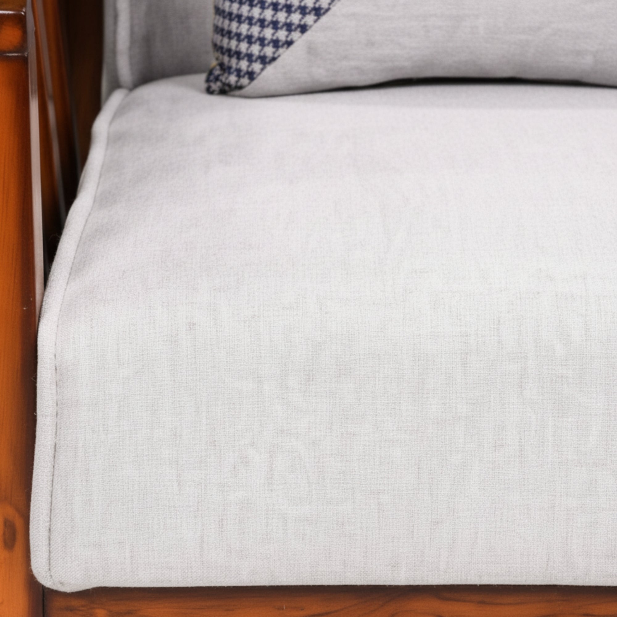 Gray cushion on a wooden chair with a checkered pillow.
