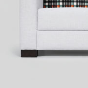 Gray upholstered bed with a plaid headboard against a white wall